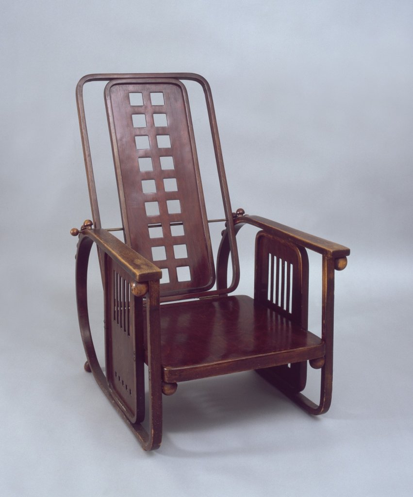 Josef Hoffmann, Křeslo polohovací, Sitzmaschine (navrženo pro sanatorium Westend v Purkersdorfu), 1905, (J. & J. Kohn), ohýbané bukové dřevo, prořezávání, textilní polštáře (design textilu Joh. Backhausen & Söhne); v. 110 cm, š. 65 cm, h. 82 cm, polštáře: 105×55×4 cm, 28×75×10 cm. Muzeum umění Olomouc