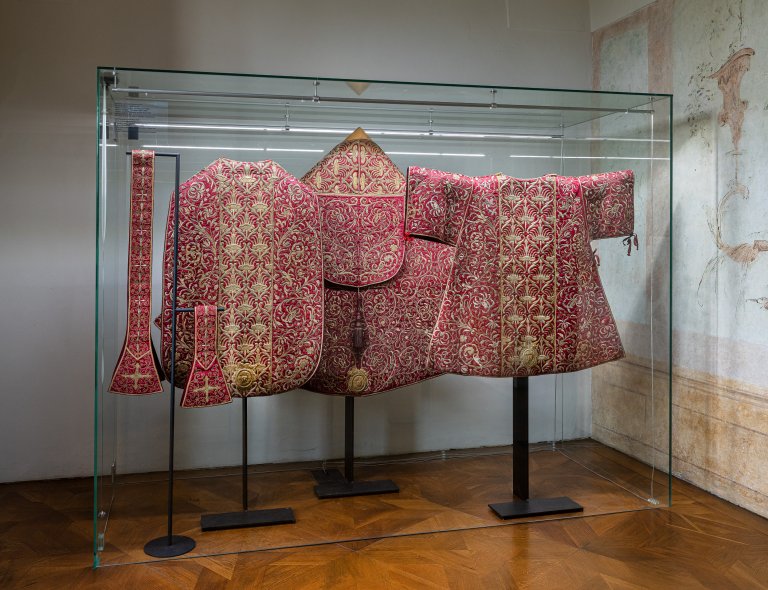 Červený parament biskupa Karla z Lichtensteinu-Castelcorna: kasule, štola, manipul, pluviál a dalmatika, kolem 1680–1690, výšivka zlatými dracouny na sytě červeném hedvábném atlasu. Římskokatolická farnost sv. Václava v Olomouci. Foto: MUO – Markéta Ondrušková